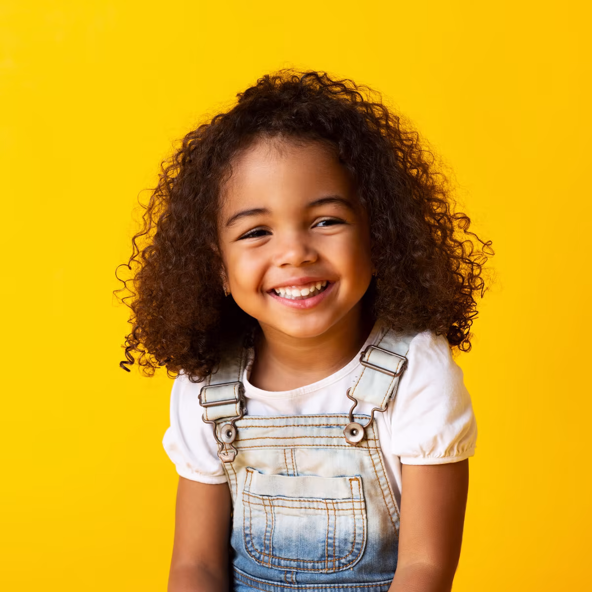Happy little girl with curly hair smiling